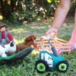 Children's toy farm set on grass with a child in pink dress partially visible