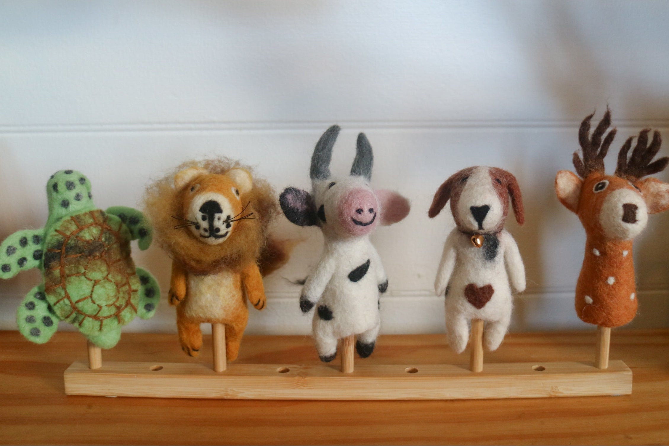 Set of plush animal toys on a wooden stand against a white wall.